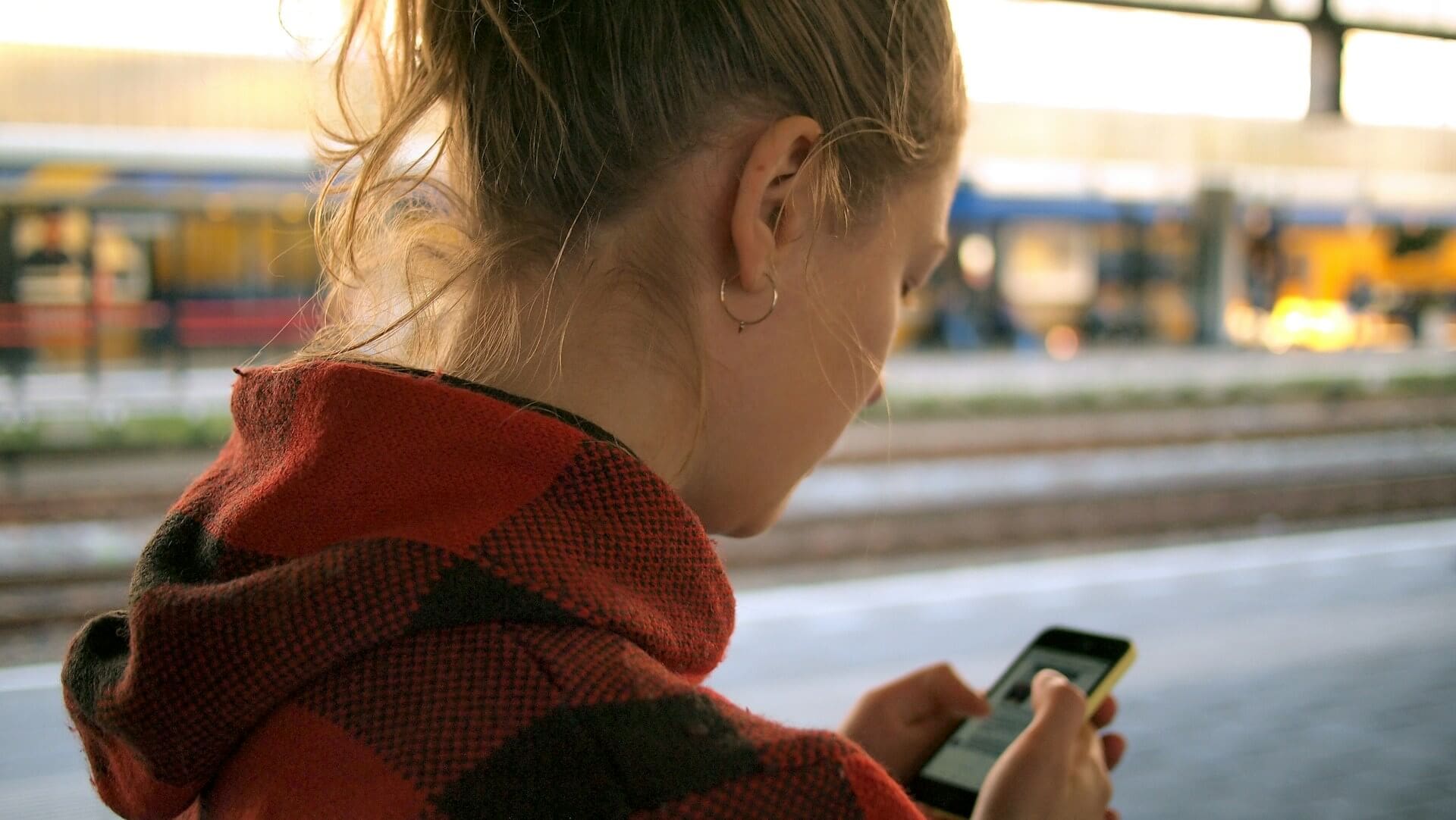 Kvinna som har lyckad roaming utomlands på en tågstation.